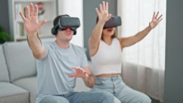 Όμορφο ζευγάρι παίζει βιντεοπαιχνίδι χρησιμοποιώντας γυαλιά εικονικής πραγματικότητας στο σπίτι - Πλάνα, βίντεο