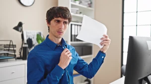 Joven trabajador de negocios hispano usando documentos como un ventilador de mano en la oficina - Metraje, vídeo