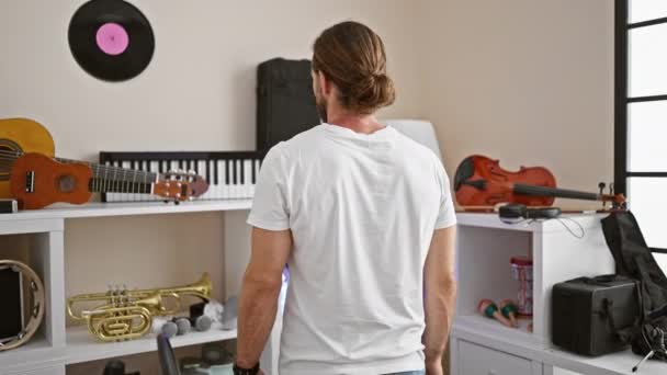 Молодий іспаномовний музикант посміхається впевнено стоячи зі зброєю перетнув жест на музичній студії - Кадри, відео