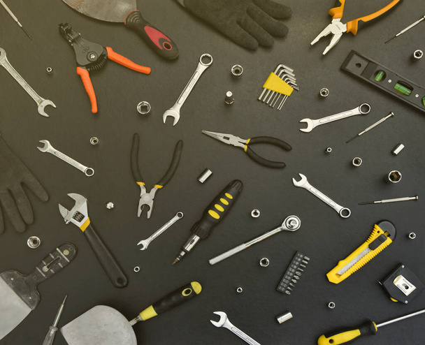 Trousse à outils bricoleur sur table en bois noir. Nombreuses clés et tournevis, pilotis et autres outils pour tout type de travaux de réparation ou de construction. Ensemble d'outils de réparateur - Photo, image