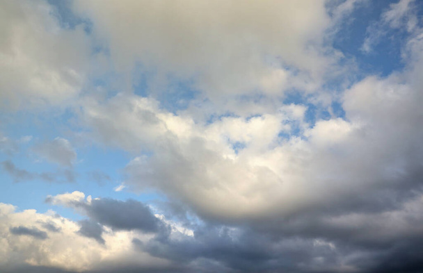 Kauniita pilvimuodostelmia taivaalla auringonvalo takanaan. Valkoisia pilviä dramaattisella sinisellä taivaalla illalla - Valokuva, kuva