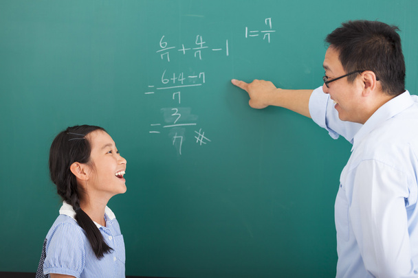 teacher with a little girl discussing  in classroom - 写真・画像