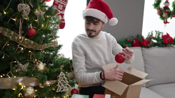 Giovane uomo ispanico decorazione albero di Natale a casa - Filmati, video