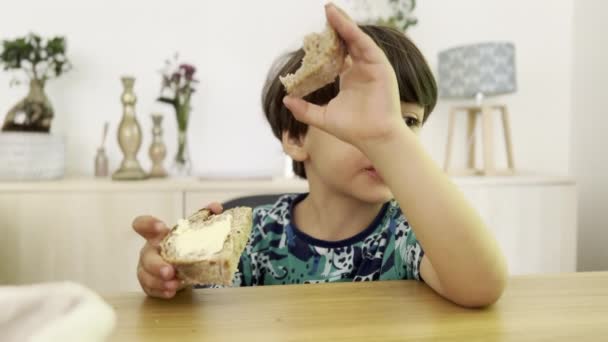 Kid sabores de pan con mantequilla para el desayuno en la mesa - Metraje, vídeo