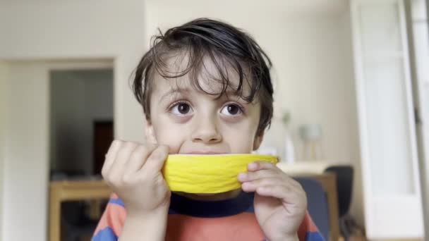 Boldog gyermek kényeztető sárga dinnye délutáni snack - kézi evés, arc borított gyümölcslé - Felvétel, videó