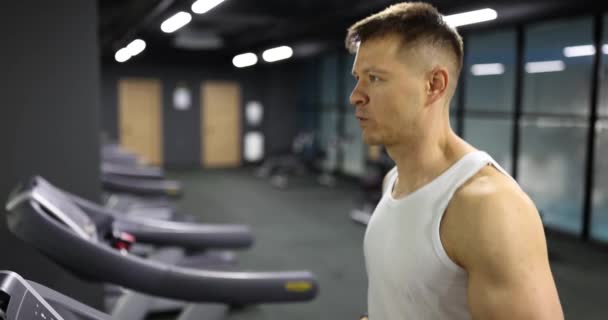 Atleta activo haciendo entrenamiento cardio intenso para quemar calorías. Retrato del joven corriendo en la cinta - Imágenes, Vídeo