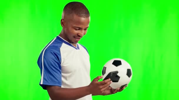 Voetbal, sport en zwarte man met telefoon op groen scherm in studio geïsoleerd op een achtergrond mockup. Voetbal, mobiele en gelukkige Afrikaanse atleet met bal voor training, training of fitnessoefening - Video