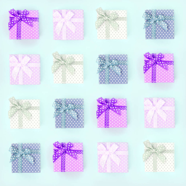 Auf violettem Hintergrund stapeln sich kleine farbige Geschenkboxen mit Schleifen. Minimalismus flache Lagemuster von oben. - Foto, Bild