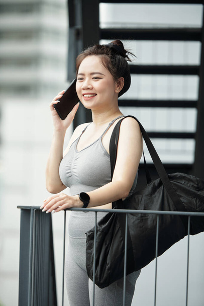 Mosolygó fiatal nő tornatáska hívás telefonon - Fotó, kép