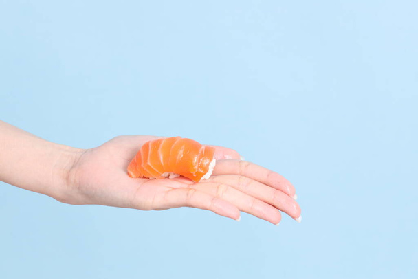 The Asian woman hand holding sushi in the blue background. - Foto, Imagen