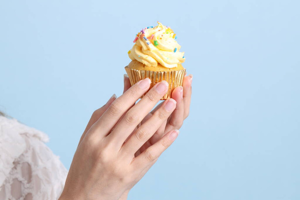 de aziatische vrouw eten cupcakes op de blauwe achtergrond. - Foto, afbeelding