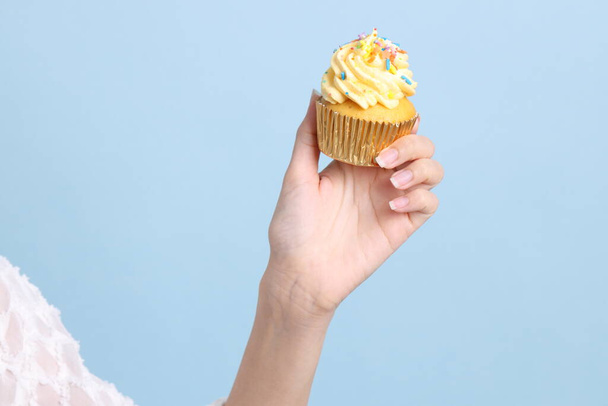 Азиатка ест кексы на голубом фоне. - Фото, изображение