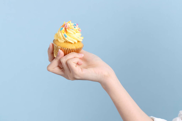 Die Asiatin isst Cupcakes auf blauem Hintergrund. - Foto, Bild