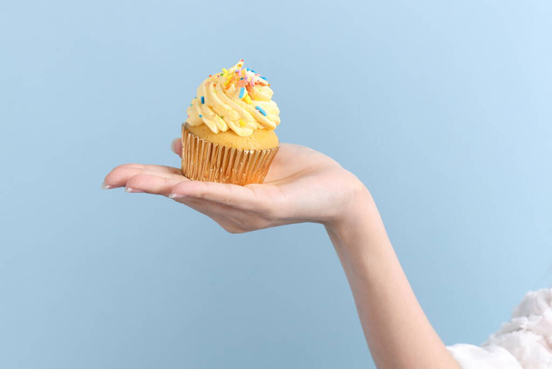 de aziatische vrouw eten cupcakes op de blauwe achtergrond. - Foto, afbeelding