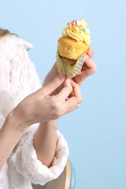 La mujer asiática comiendo cupcakes en el fondo azul. - Foto, Imagen
