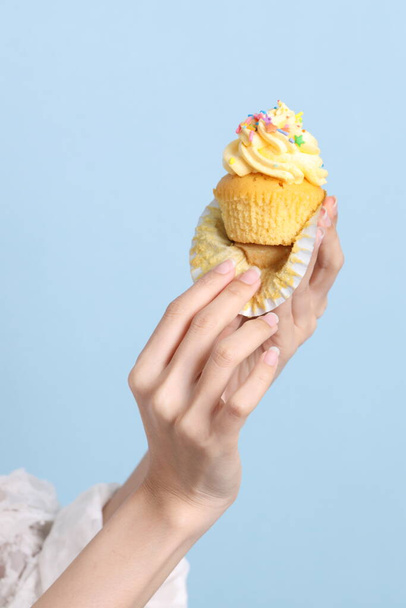 The Asian woman eating cupcakes on the blue background. - Photo, Image