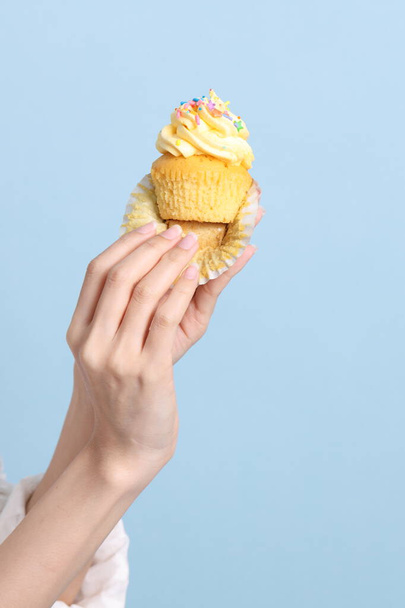 Asijské žena jíst cupcakes na modrém pozadí. - Fotografie, Obrázek