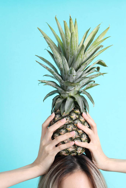The Asian woman hand holding pineapple in the green background. - Photo, Image
