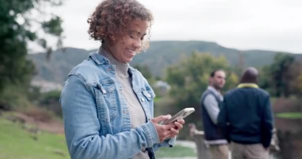 Happy, typing and woman with a phone in nature for communication, social media or a chat. Smile, email and a young girl with a mobile for an app notification, conversation or search online at a park. - Metraje, vídeo