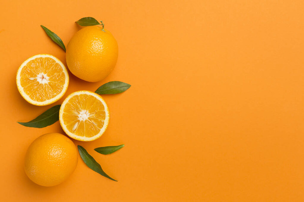 Flat lay with fresh oranges and leaves on color background. - Foto, afbeelding