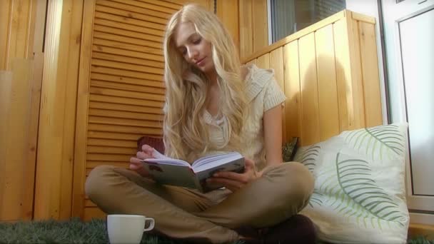 kobieta pijąca kawę i czytająca książkę - Materiał filmowy, wideo