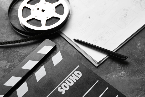 Storyboard con película clapper y carrete de película sobre fondo oscuro - Foto, Imagen