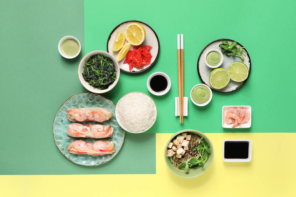 Композиція зі смачними китайськими стравами та паличками на кольоровому фоні - Фото, зображення