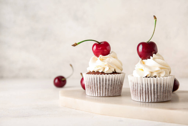 Tábla ízletes cseresznyés cupcakes könnyű háttér - Fotó, kép