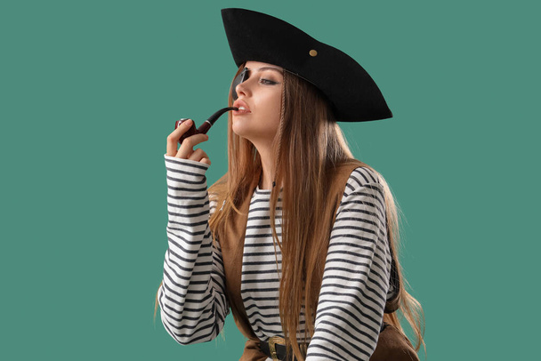 Schöne Piratin Pfeife rauchend auf grünem Hintergrund - Foto, Bild