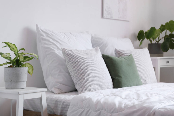 Gemütliches Bett mit weißer Decke und Kissen im hellen Schlafzimmer - Foto, Bild