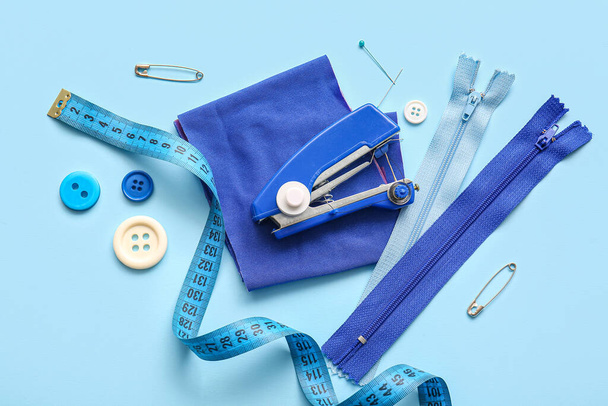 Máquina de coser manual con diferentes suministros sobre fondo azul - Foto, Imagen