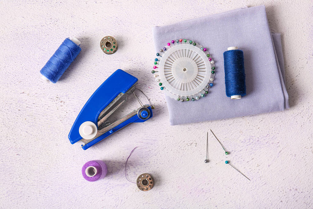 Máquina de coser manual con diferentes suministros sobre fondo blanco grunge - Foto, Imagen