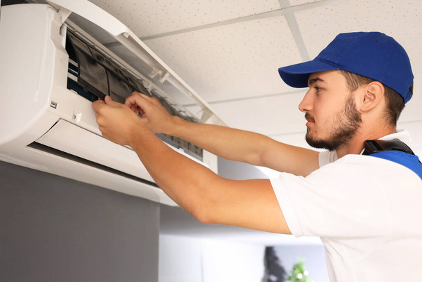 Man technicus repareren airconditioner in de kamer - Foto, afbeelding