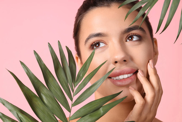 Young woman with beautiful lips and palm leaves on pink background, closeup - Photo, Image