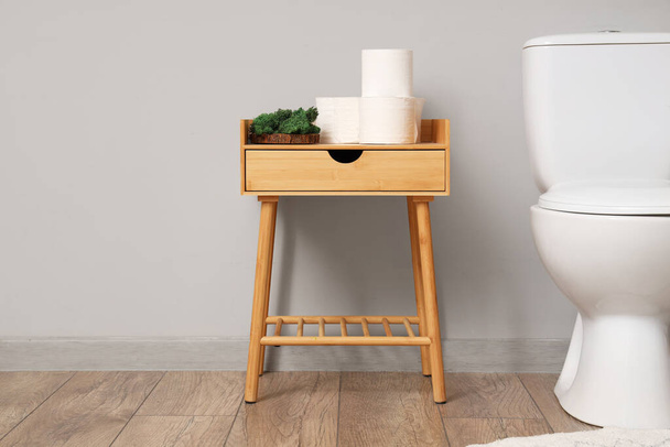 Çağdaş tuvaletlerde kağıt rulolarlı ahşap masa ve çalı çırpı kabının yanında saksı, yakın plan. - Fotoğraf, Görsel