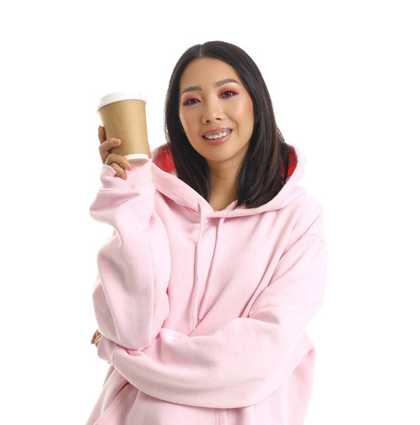Mujer asiática joven con capucha rosa con taza de café sobre fondo blanco - Foto, Imagen