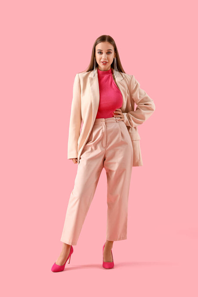 Stylish young woman in suit on pink background - Foto, imagen