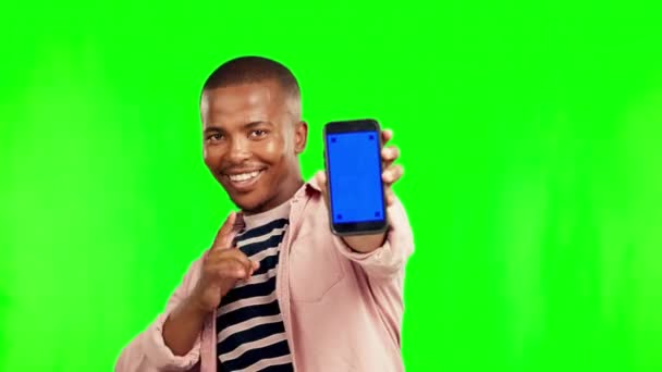 Vrolijke zwarte man, telefoon en mockup op groen scherm voor reclame tegen een studio achtergrond. Portret van Afrikaanse man die wijst met mobiele smartphone app of tracking markers op mock up ruimte. - Video