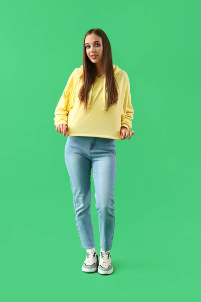 jonge vrouw in hoodie op groene achtergrond - Foto, afbeelding