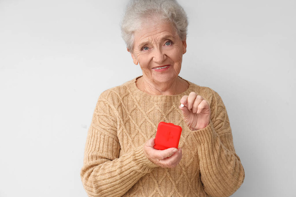 Senior woman with pill box on light background - Photo, Image