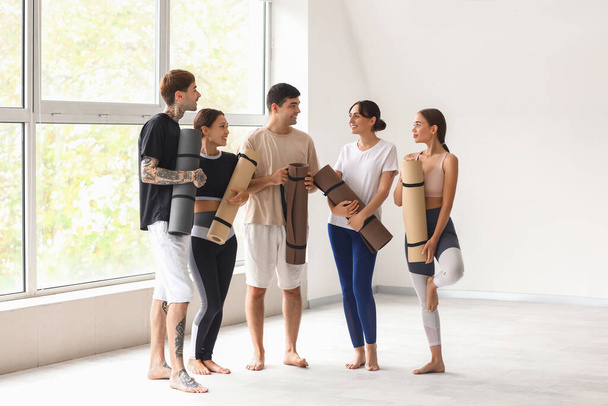 Group of sporty young people with yoga mats in gym - Photo, Image
