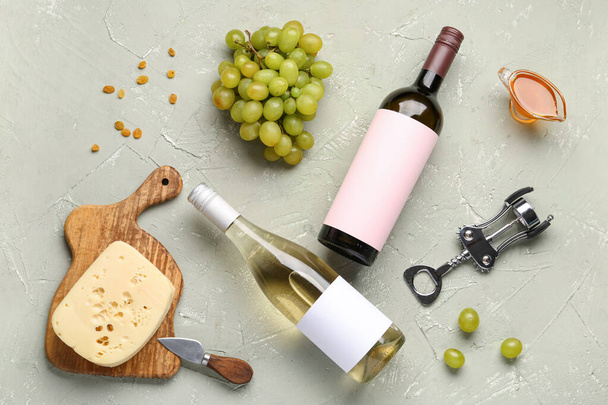 Бутылки вина с чистыми этикетками и виноград на зеленом фоне - Фото, изображение