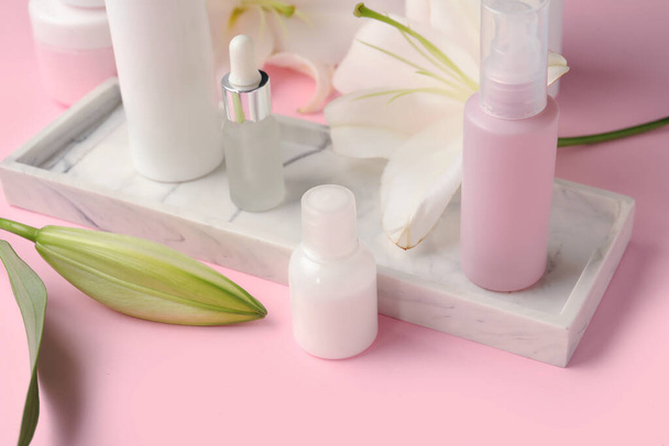 Placa com produtos cosméticos e flores de lírio em fundo rosa - Foto, Imagem