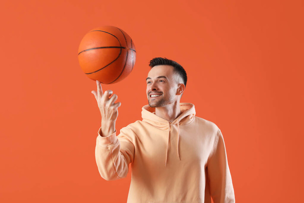 Ευτυχισμένος νεαρός άνδρας με μπάλα σε πορτοκαλί φόντο - Φωτογραφία, εικόνα