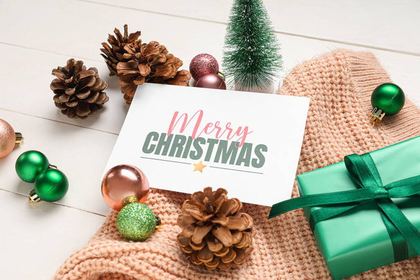 Prachtige kerstcompositie met wenskaart, geschenkdoos en decor op witte houten ondergrond - Foto, afbeelding