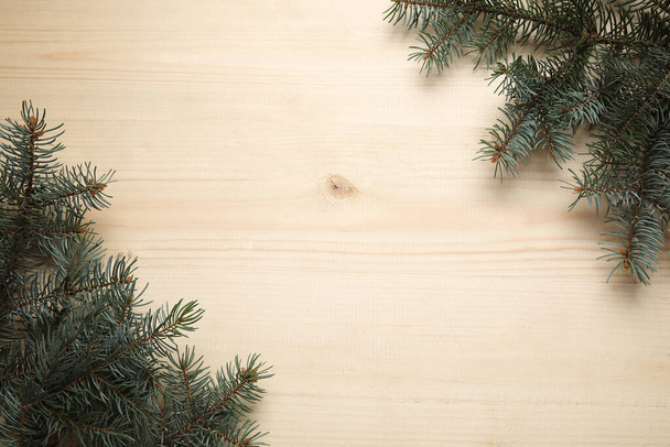 Beautiful fir branches on beige wooden background - Photo, Image