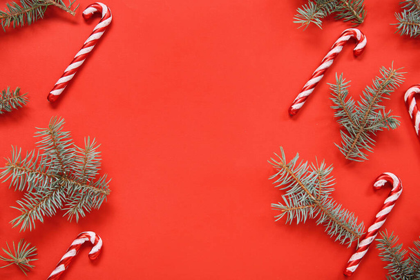 Σύνθεση με όμορφα χριστουγεννιάτικα στολίδια και κλαδιά ελάτης σε κόκκινο φόντο - Φωτογραφία, εικόνα