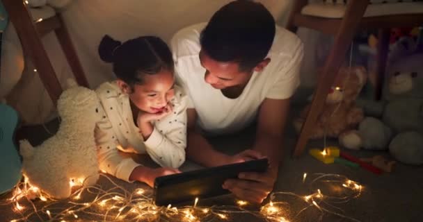 Namiot, ojciec i dziewczyna na tablecie w nocy oglądają filmy, gry online i bajki na dobranoc ze światłami. Szczęśliwa rodzina, uśmiech i tata z dzieckiem w sypialni na technologii cyfrowej do tworzenia więzi, relaks i miłość. - Materiał filmowy, wideo