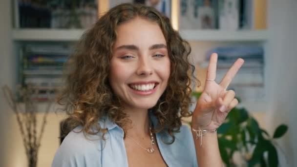 Modern fashionable female fooling around posing with V sign, blowing air kiss, laughing, grimacing. 20s girl posing indoors. Beautiful hipster model dancing funny dance in stylish apartment background - Footage, Video