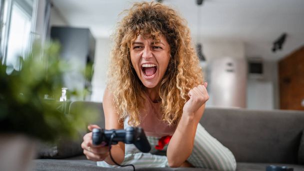 Jeden dospělý mladý kavkazský žena hrát konzole videohry držet joystick regulátor doma bavte se, zatímco brzda z domácí práce skutečný člověk volný čas koncept kopírovat prostor - Fotografie, Obrázek